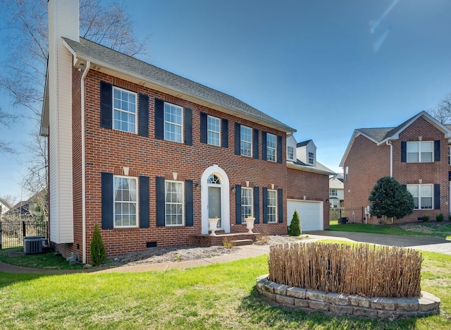 colonial-style house featuring fence, concrete driveway, a front yard, brick siding, and a chimney