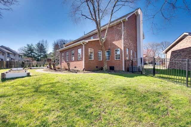 rear view of house with crawl space, a lawn, brick siding, and fence