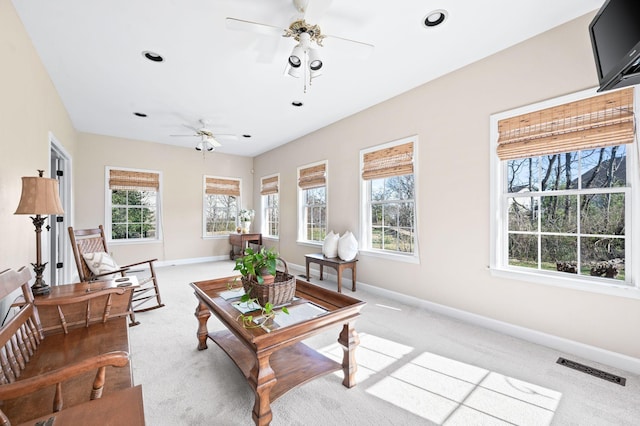 living area with visible vents, light carpet, baseboards, and ceiling fan