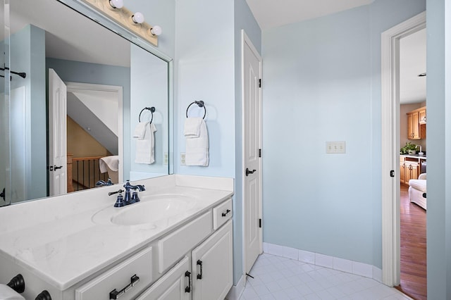 ensuite bathroom featuring tile patterned flooring, connected bathroom, vanity, and baseboards