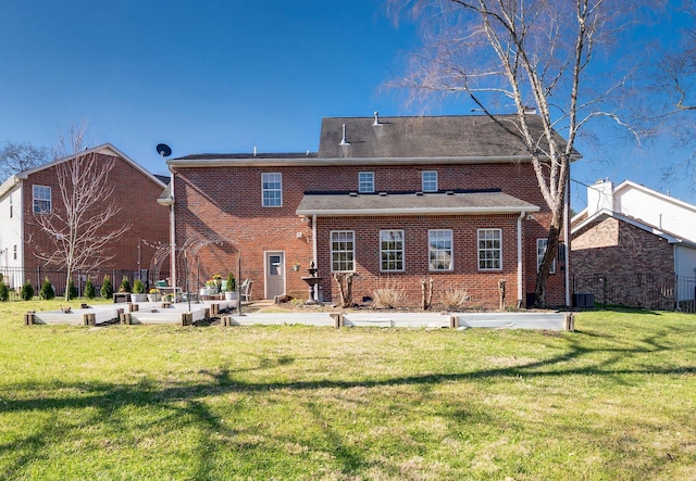 rear view of house with a garden, a yard, brick siding, and fence