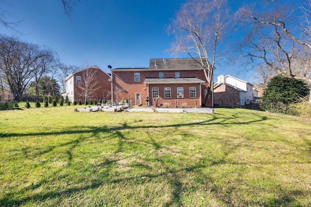 back of property with brick siding, fence, and a lawn