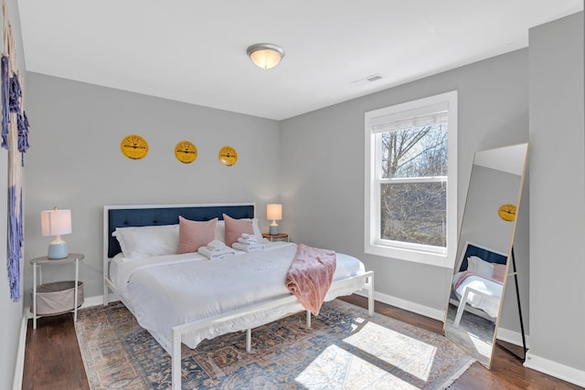 bedroom with visible vents, wood finished floors, and baseboards