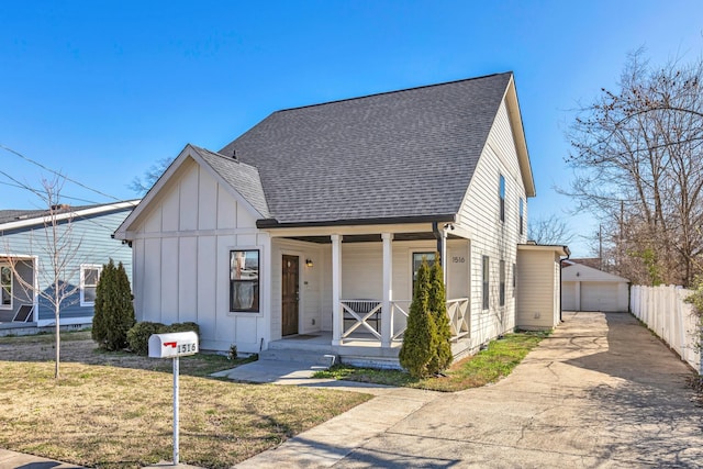 modern inspired farmhouse featuring board and batten siding, a shingled roof, a porch, a garage, and an outbuilding