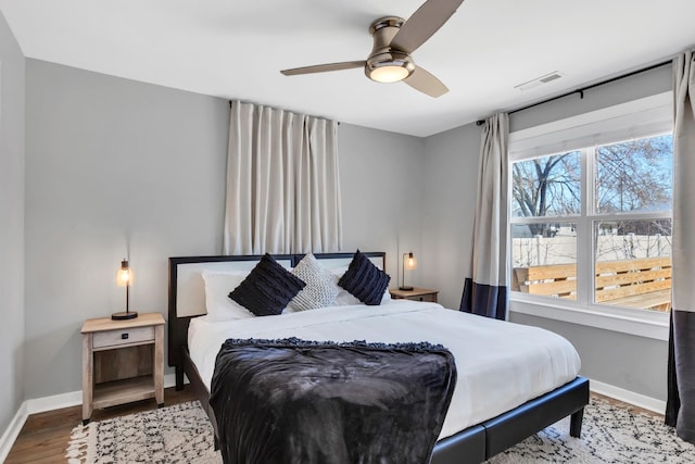 bedroom featuring ceiling fan, wood finished floors, visible vents, and baseboards