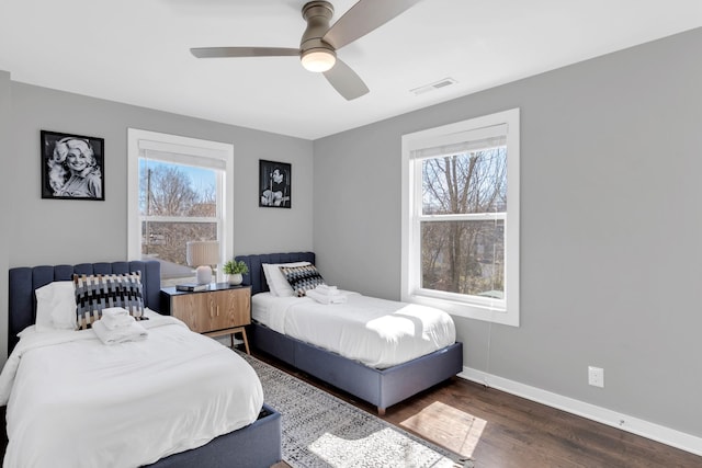 bedroom featuring visible vents, multiple windows, baseboards, and wood finished floors