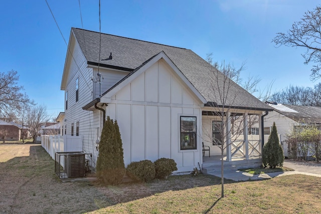 exterior space featuring board and batten siding, a shingled roof, and a front lawn