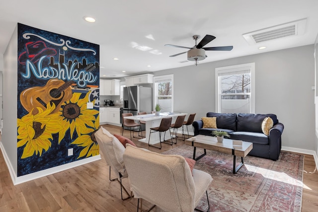 living area with visible vents, baseboards, ceiling fan, light wood-type flooring, and recessed lighting