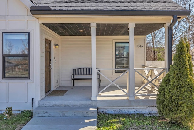 view of exterior entry with board and batten siding, a porch, and a shingled roof