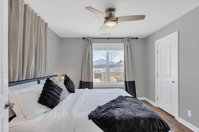 bedroom featuring visible vents, ceiling fan, baseboards, and wood finished floors