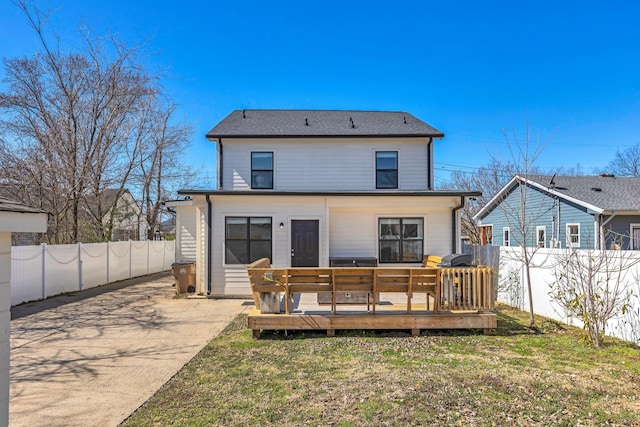 rear view of house with a deck, fence private yard, and a yard