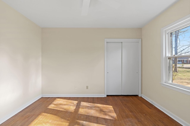 unfurnished bedroom with a closet, baseboards, and wood finished floors