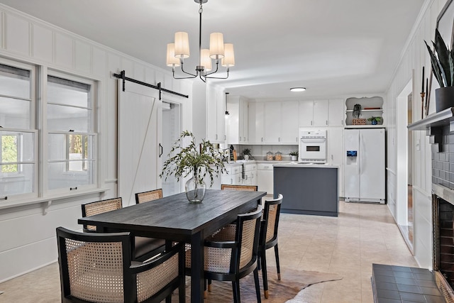 dining room featuring light tile patterned floors, a barn door, an inviting chandelier, and crown molding