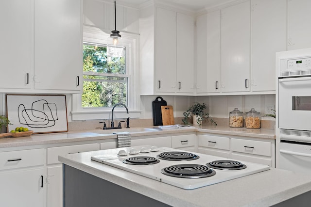 kitchen featuring white electric stovetop, light countertops, and a sink