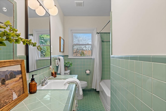 bathroom with visible vents, toilet, shower / tub combo with curtain, tile walls, and vanity