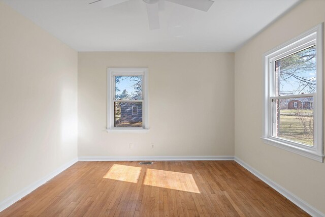 empty room with a wealth of natural light, ceiling fan, baseboards, and wood finished floors