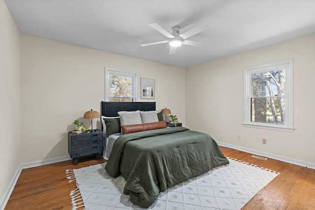 bedroom with visible vents, multiple windows, baseboards, and wood-type flooring