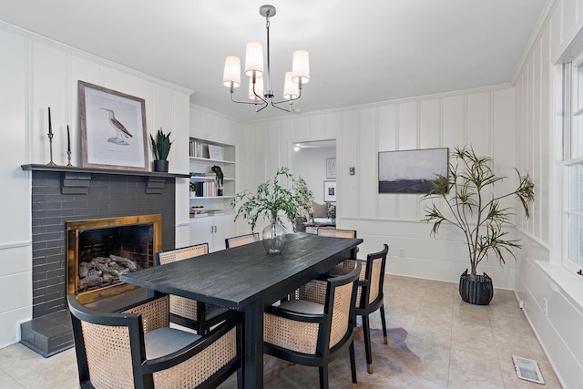 dining area featuring visible vents, built in shelves, a fireplace, and a decorative wall