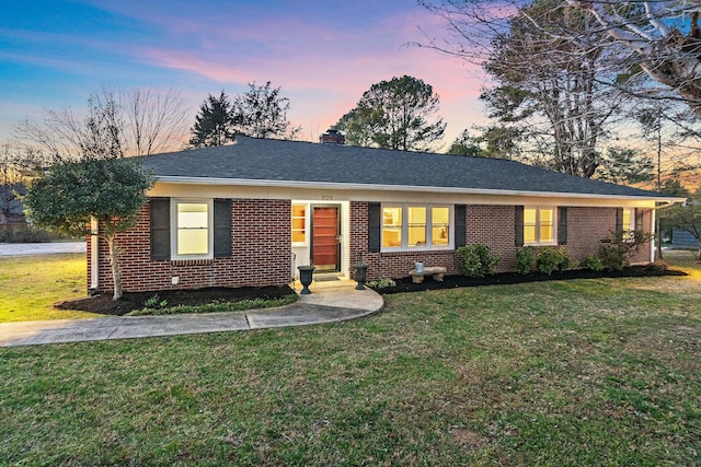 single story home with brick siding, a chimney, a front lawn, and roof with shingles