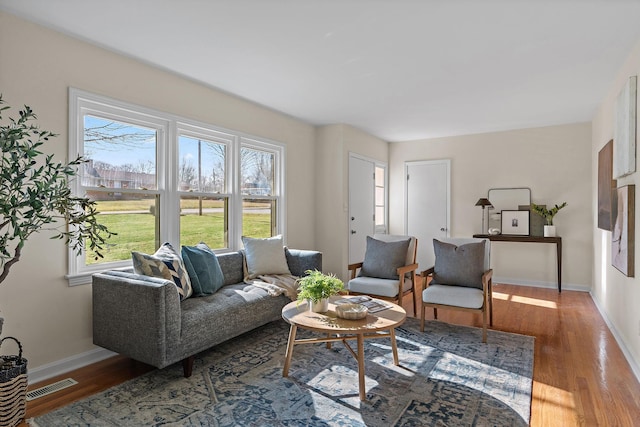 living area featuring wood finished floors, visible vents, and baseboards