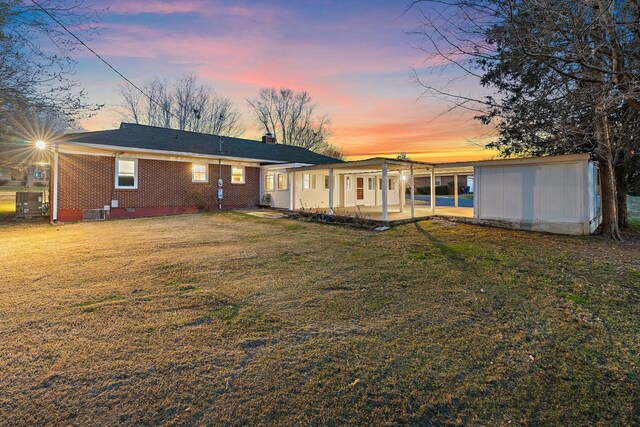 rear view of property with a yard, a chimney, crawl space, a patio area, and brick siding