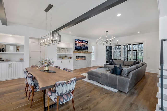 dining room featuring a glass covered fireplace, beamed ceiling, and wood finished floors