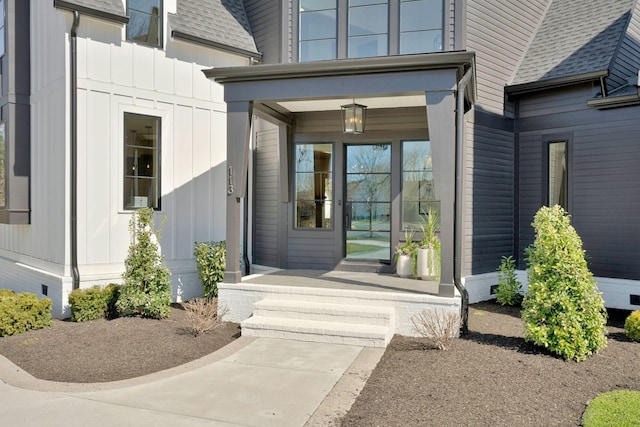 doorway to property featuring board and batten siding, covered porch, and roof with shingles