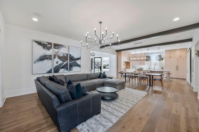 living area featuring beamed ceiling, a notable chandelier, recessed lighting, light wood finished floors, and baseboards