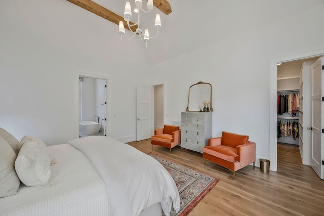 bedroom with light wood finished floors, beam ceiling, a closet, a walk in closet, and a chandelier