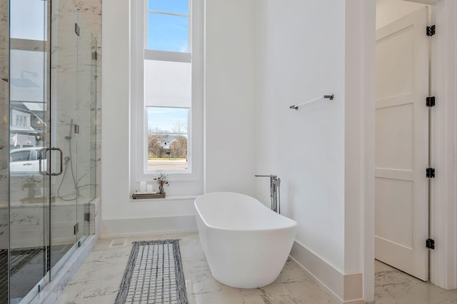 bathroom with a freestanding tub, baseboards, marble finish floor, and a shower stall