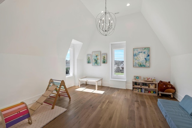 rec room with a notable chandelier, wood finished floors, baseboards, and high vaulted ceiling