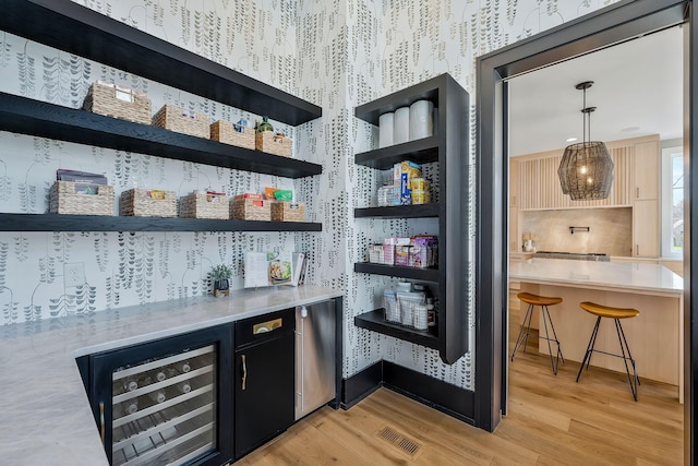 bar with visible vents, fridge, wine cooler, light wood-style floors, and wallpapered walls