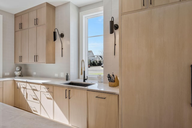 kitchen featuring tasteful backsplash, plenty of natural light, light brown cabinets, and a sink