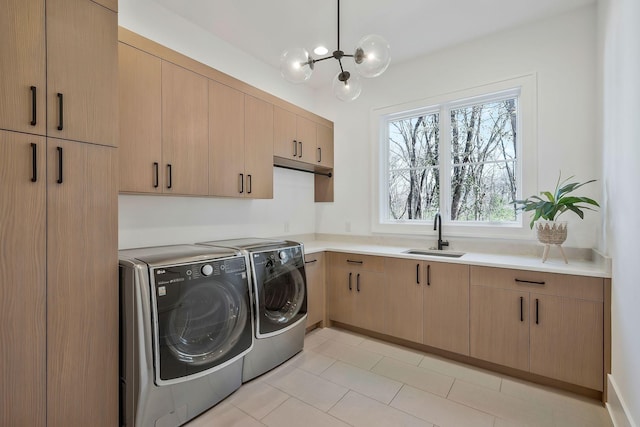 laundry area featuring an inviting chandelier, cabinet space, independent washer and dryer, and a sink