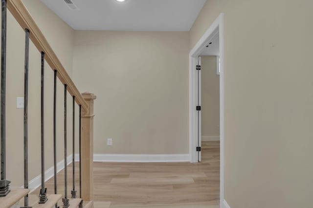 corridor with stairs, light wood-style flooring, baseboards, and visible vents