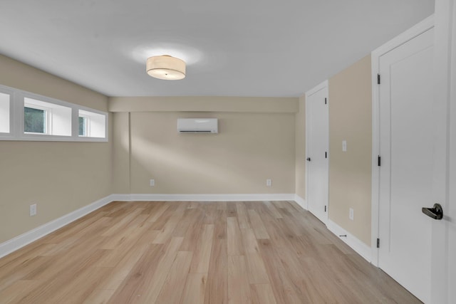 interior space with a wall mounted air conditioner, baseboards, and light wood finished floors