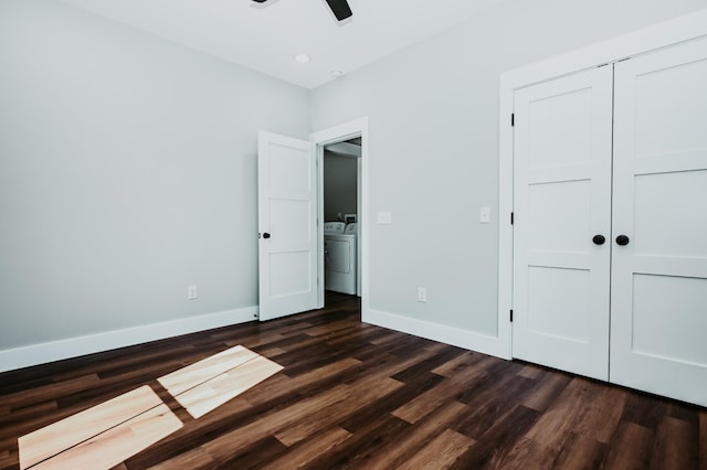 unfurnished bedroom featuring dark wood-style floors, a closet, washer / clothes dryer, and baseboards