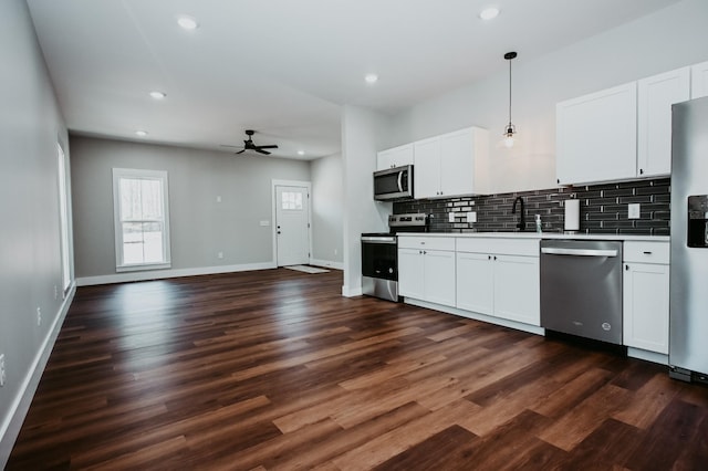 kitchen featuring dark wood-type flooring, a sink, tasteful backsplash, stainless steel appliances, and baseboards