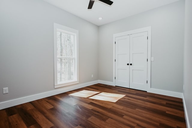 unfurnished bedroom featuring a closet, baseboards, ceiling fan, and dark wood-style flooring