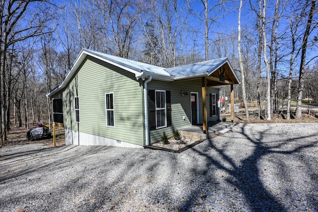 view of front of home with gravel driveway, metal roof, and crawl space