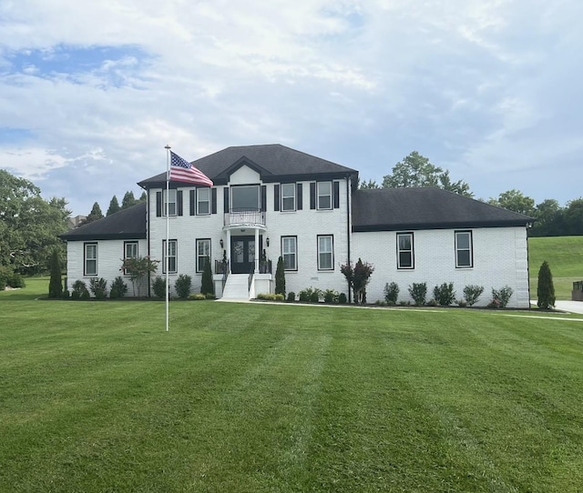 colonial inspired home featuring a front lawn and brick siding