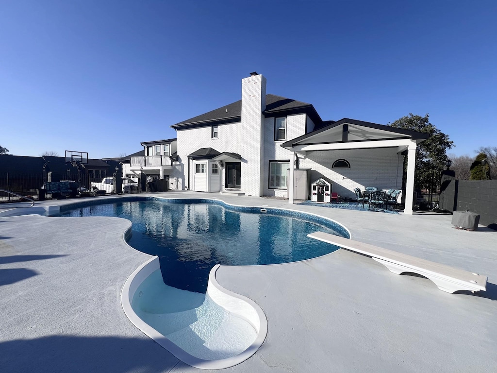 view of pool with a fenced in pool, fence, a patio, and a diving board