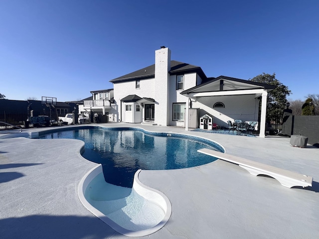 view of pool with a fenced in pool, fence, a patio, and a diving board