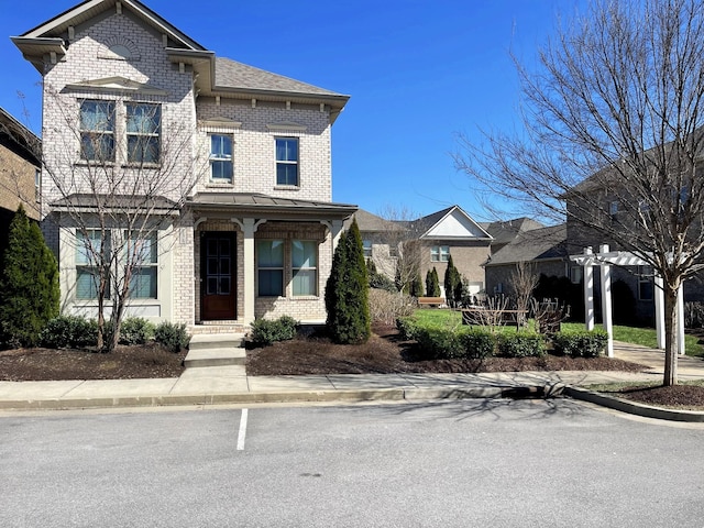 view of front of home featuring brick siding and a shingled roof