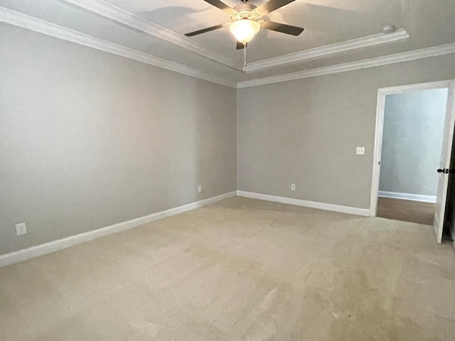 spare room with crown molding, ceiling fan, carpet, baseboards, and a tray ceiling