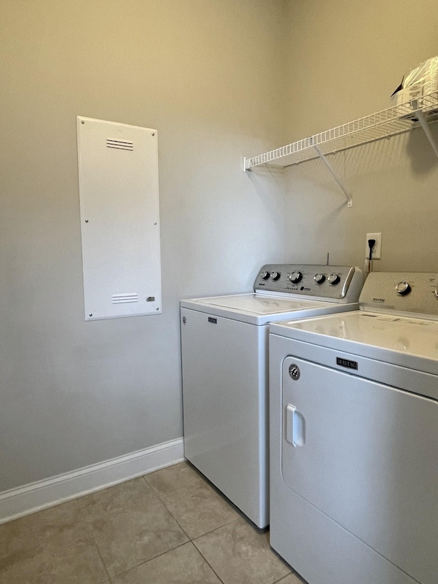 clothes washing area with laundry area, light tile patterned floors, baseboards, and washing machine and clothes dryer