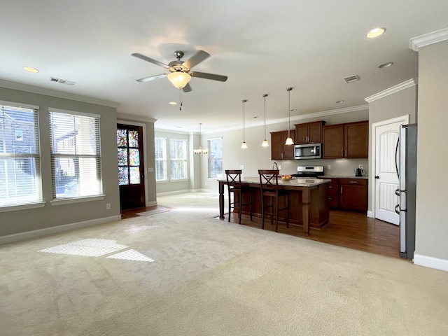 kitchen featuring visible vents, light colored carpet, appliances with stainless steel finishes, and ornamental molding