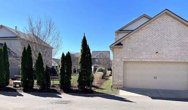 view of side of property with concrete driveway, a garage, and brick siding