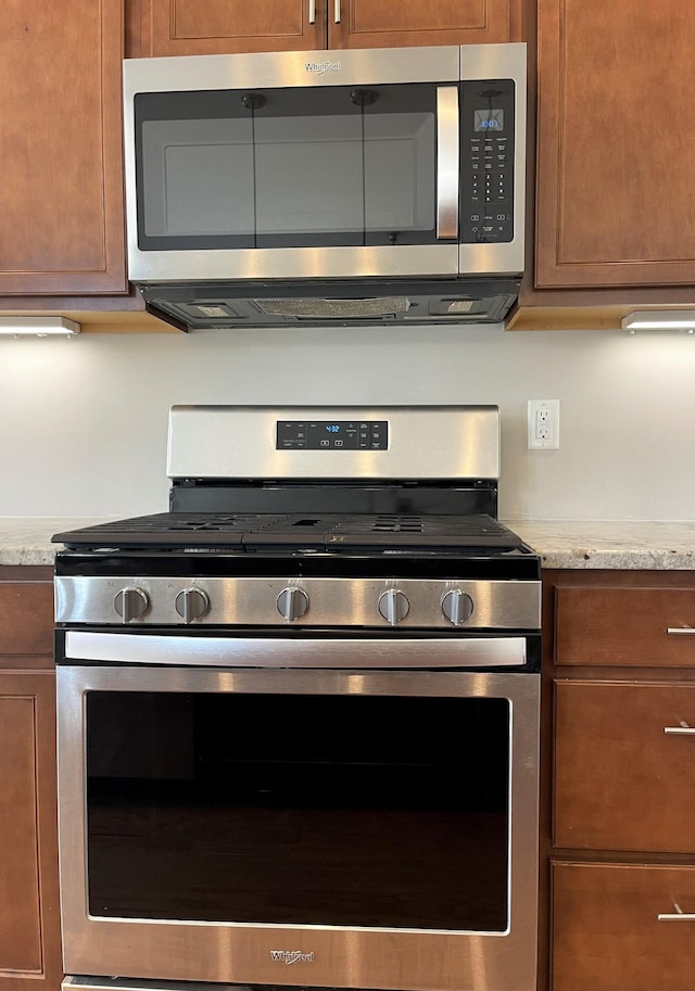 kitchen featuring stainless steel appliances, brown cabinets, and light countertops