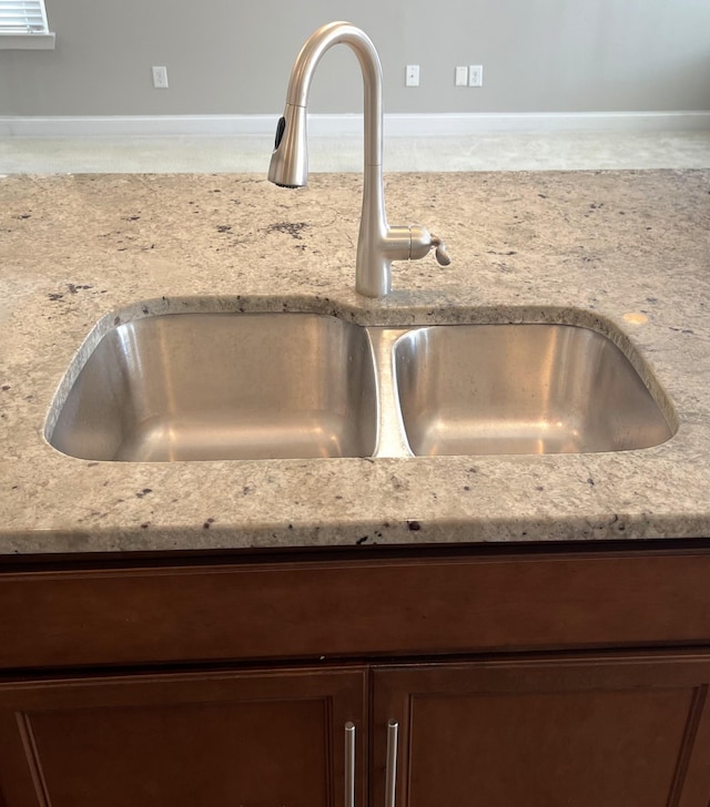 details with dark brown cabinetry, light stone countertops, and a sink